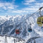 Red Gulmarg cable car moving over snow covered mountains in Kashmir