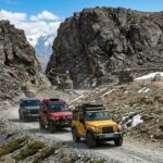 Three Mahindra Thar 4x4 vehicles driving on the world's highest motorable road at Mig La Pass on the Likaru Fukche highway in Ladakh.