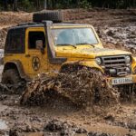 A yellow 4x4 vehicle splashing through mud during the Malabar River Festival 2026 off-road fun drive in Thusharagiri.